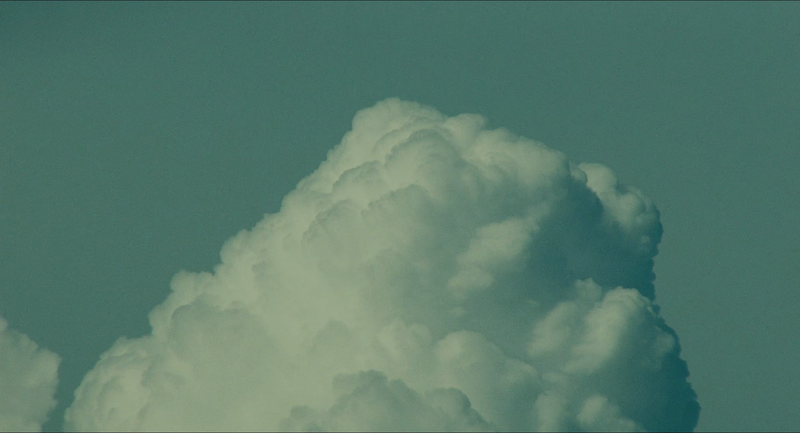 A large cloud covers the bottom half of the frame. The sky is a blueish green hue.